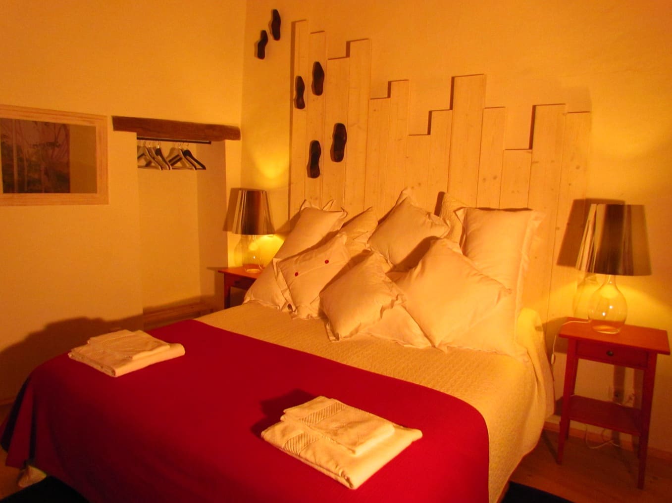 Double bed with a sculpted pallet-wood headboard and warm bedside lamps