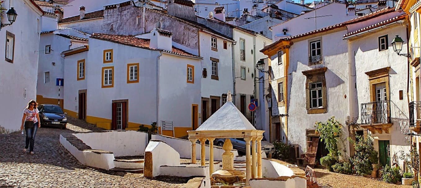 Casas caiadas e a Fonte da Vila, de colunas, num largo empedrado de Castelo de Vide